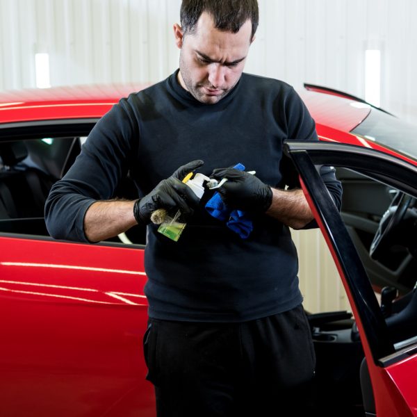 Car service worker cleans interiror with special brush.